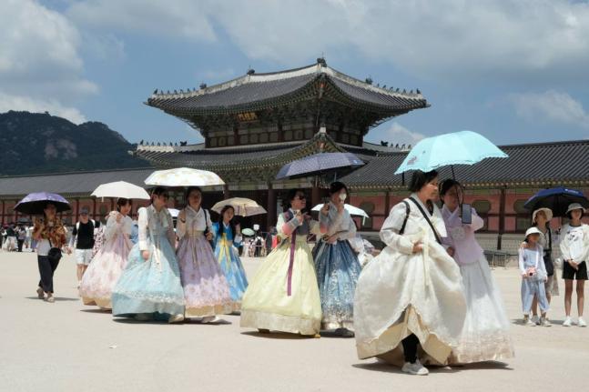 Visitors holding umbrellas to avoid sunshine leave the Gyeongbok Palace in Seoul, South Korea, Wednesday.