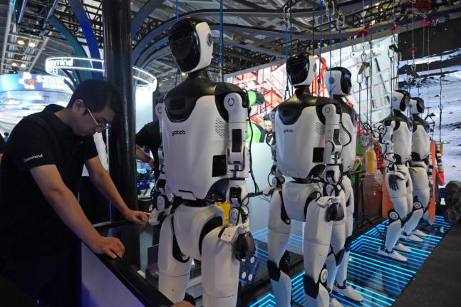 AP
A worker reacts near a line of humanoid robots displayed at the World AI Conference in Shanghai on Friday, July 17.  