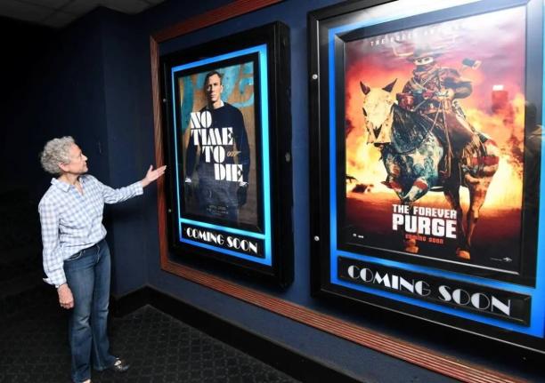 In this September 17, 2021 photo, Melanie Graham, marketing manager and director of Palace Amusement, stands in front of show posters at the company’s Carib 5 cinema in Kingston. 