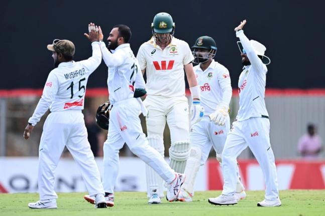 Pat Cummins (centre) of Australia walks from the field after being dismissed by Mehidy Hasan Miraz (second left) of Bangladesh during play on day four of the first cricket Test in Darwin, Australia, Sunday, August 16, 2026.  