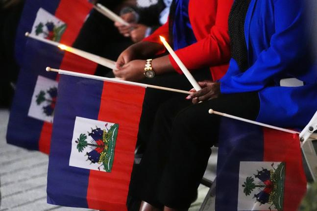 FILE - People hold Haitian flags and candles during a vigil at the Little Haiti Cultural Complex after a federal judge blocked the Trump administration from ending temporary immigration status, or TPS, for Haitians, Feb. 3, 2026, in North Miami. (AP Photo/