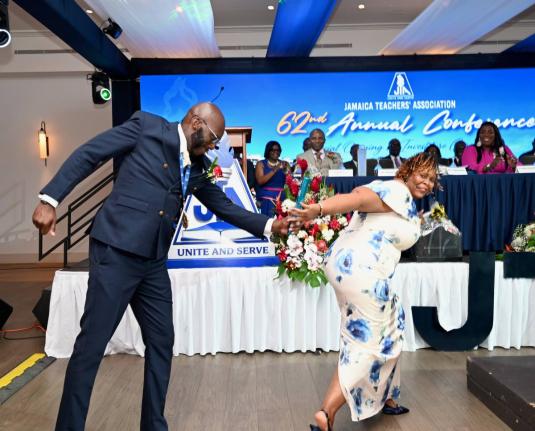 Immediate Past President Mark Malabver passes the baton to La Sonja Harrison, the newly installed president of the Jamaica Teachers’ Association, during the investiture ceremony at the association’s 62nd Annual Conference at the Ocean Coral Spring Hote