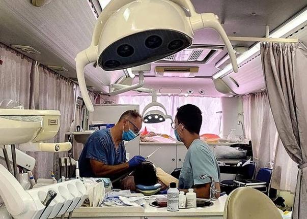 Dr Adam Szymczak (left) and his son, Justin, treat a patient inside Great Shape’s mobile dental clinic during a dental mission at the Ocho Rios High School grounds.