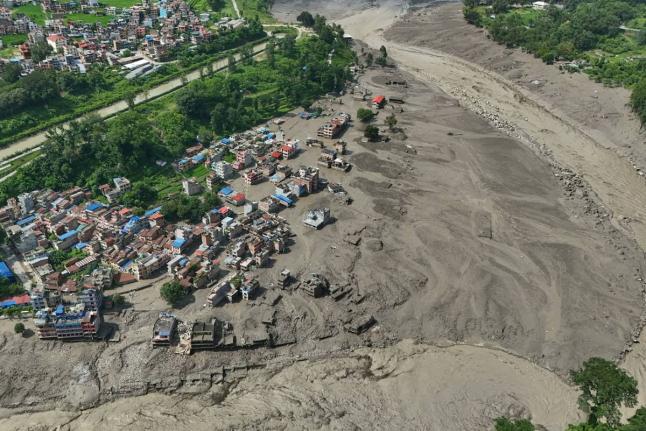Damaged houses stand precariously near the swollen, debris-choked banks of the Trishuli River after flash floods in Nepal’s Nuwakot district yesterday.