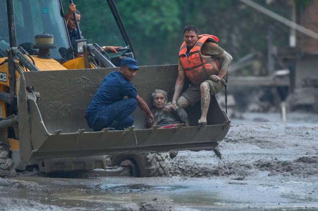 Rescuers use an earthmover to carry a victim of the flash flooding to safety along the Trishuli River in Nepal's Nuwakot district on Wednesday. - AP photo