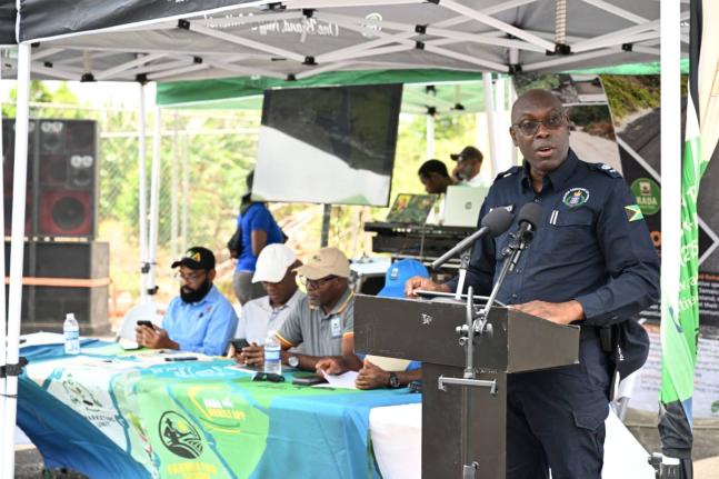 Superintendent of Police Colridge Minto (right) speaks at the opening of the Newcombe Valley to Amos Lane farm road in Pedro Plains, St Elizabeth. Seated at the head table are (from left) Richard Solomon, mayor of Black River; Karle Whyte, councillor for t
