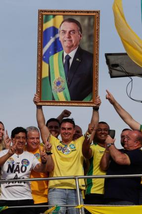Opposition presidential candidate Flavio Bolsonaro holds a photo of his father, former President Jair Bolsonaro, as he rides a boat during a campaign rally ahead of the October general election in Angra dos Reis, Rio de Janeiro state, Brazil, Saturday.