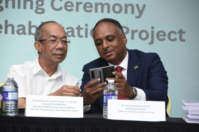 Deputy Prime Minister Dr Horace Chang (left) examines the proposed design for the Old Fort Craft Market in Montego Bay with Jamaica Social Investment Fund Managing Director Omar Sweeney.