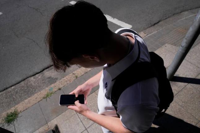 A teenage boy using his phone in Sydney, Australia, on November 8, 2024.  