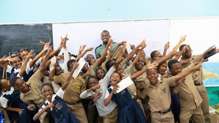 Students share a moment with Olympic champion Usain Bolt after receiving support from the Usain Bolt Foundation.