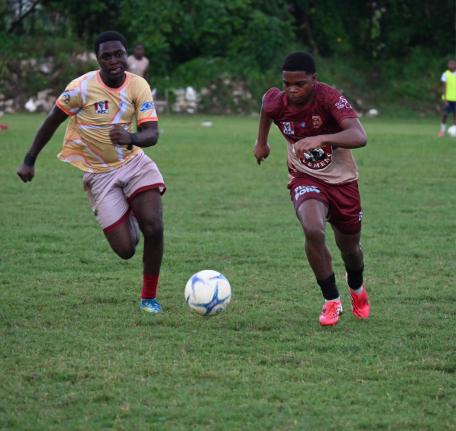 St James High’s Davano Brown (left) and Herbert Morrison Technical High’s Aiden James chase the ball during their ISSA daCosta Cup preliminary round game at Herbert Morrison playing field yesterday. St James won 3-2.