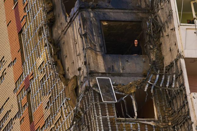 A woman peers from a window of a partially damaged residential building following a Russian drone attack in Kyiv, Ukraine, September 9.
