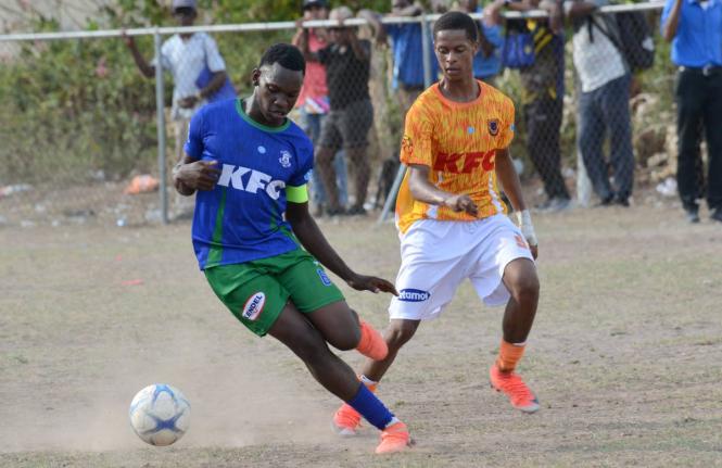 Demarco Hunter (left)  of Norman Manley High shields the ball from Malachi Matthews of Donald Quarrie High during their ISSA Manning Cup match at Maxfield Park yesterday.