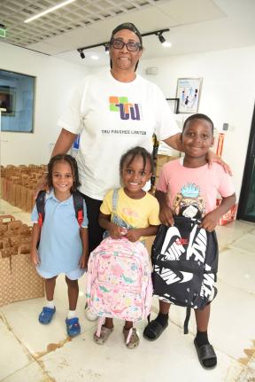 Sharon Harris, managing  director, Tru Finishes Limited, presents schoolbags to children from the Maxfield Avenue area during the company’s annual back-to-school treat for children in the area recently.