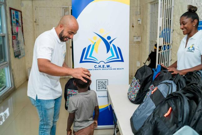 C.H.E.W. Foundation CEO, Sereste Bell (left) presents a backpack filled with school supplies to a participant of SOS Children’s Villages Jamaica. Looking on is the foundation’s chairperson, Dr Leanne Levers.