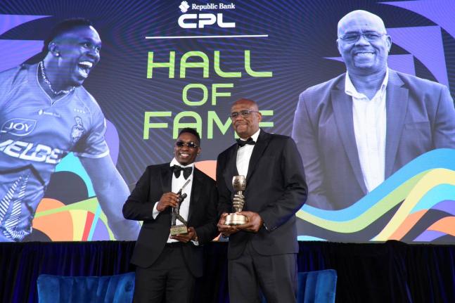 Dwayne Bravo (left) and Ian Bishop display the trophies they earned during a Caribbean Premier League Hall of Fame induction ceremony at the Hilton Barbados on Tuesday.  