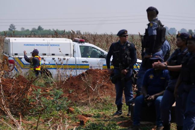 Forensic investigators work at the site where the body of a woman was discovered on the outskirts of Johannesburg, South Africa, Thursday.