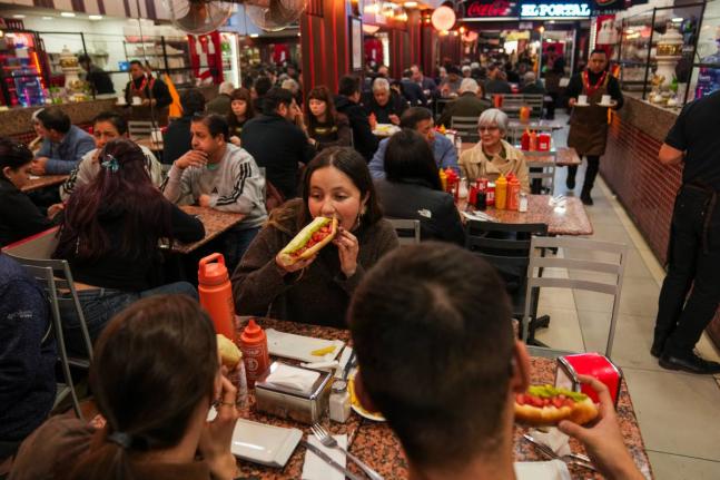 Antonia Bravo eats a “completos”, traditional Chilean hot dogs topped with mashed avocado, diced tomatoes and mayonnaise, at the “El Portal Ex Bahamondes” restaurant in downtown Santiago, Chile.