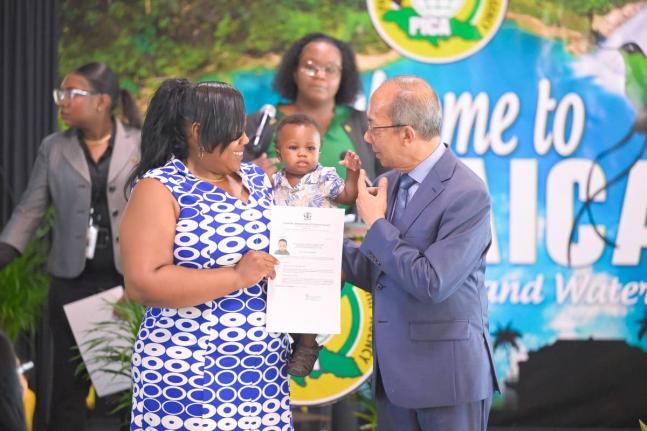 Deputy Prime Minister and Minister of National Security and Peace, Dr Horace Chang, shares a moment with Jamaican citizen, Sharmaine Campbell Burrell (left), and her son, Kejaun Burrell, as they display a certificate formalising his citizenship during the 
