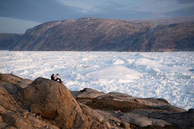 NYU student researchers sit on top of a rock overlooking the Helheim glacier in Greenland, August 16, 2019.