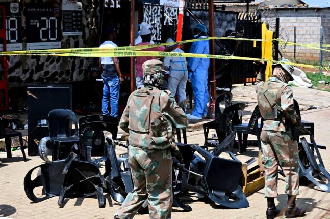 Forensic officers and the army members are seen at scene of a mass shooting on Saturday night when suspects opened fire at a bar in Wedela township, southwest of Johannesburg, South Africa, Sunday, Sept. 27, 2026. (AP Photo)