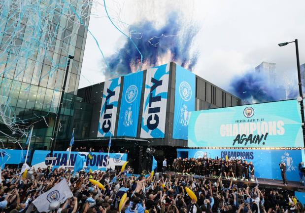 Flares and tape are set off as Manchester City’s players celebrate on stage while fans watch the winners parade as the team celebrates winning the English Premier League title in Manchester, England, Monday, May 23, 2022. 