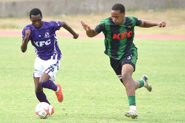 Kingston College’s Kajay Fletcher (left) comes under pressure from Calabar’s Miguel Logan during their ISSA Walker Cup football match at the National Stadium East field yesterday.