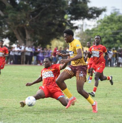 Cornwall College’s Tyrese Scott lunges into a tackle against Manchester High’s  Samuel Smith during their ISSA Ben Francis KO round-of-16 football match at Manchester yesterday. 